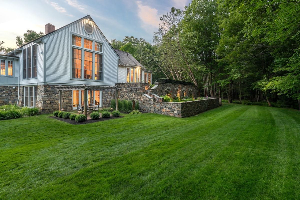 Rear view of the house with with a large lawn and trees.