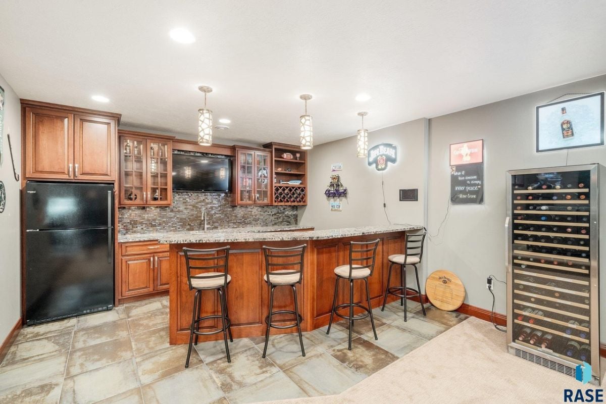 Bar with granite counter, TV and a refrigerator.
