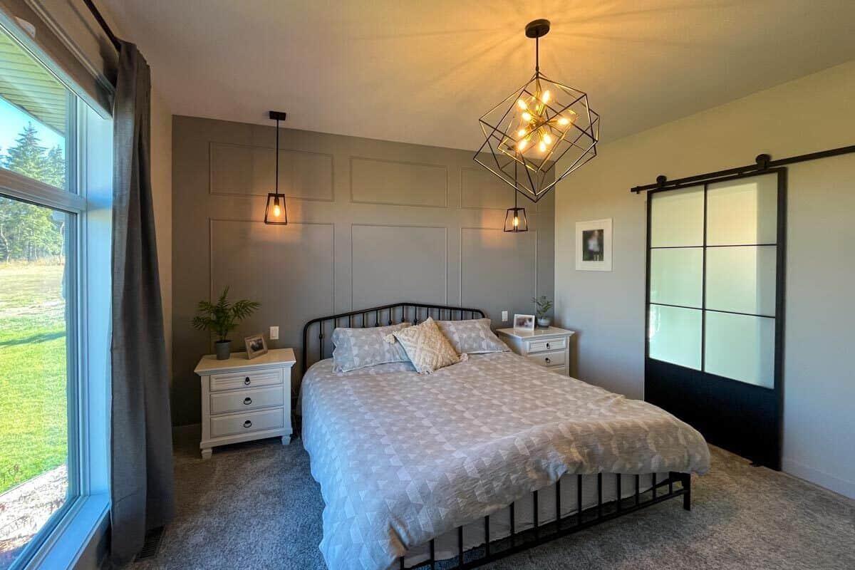 Primary bedroom with warm pendant lights and a dark wood bed against the paneled accent wall.