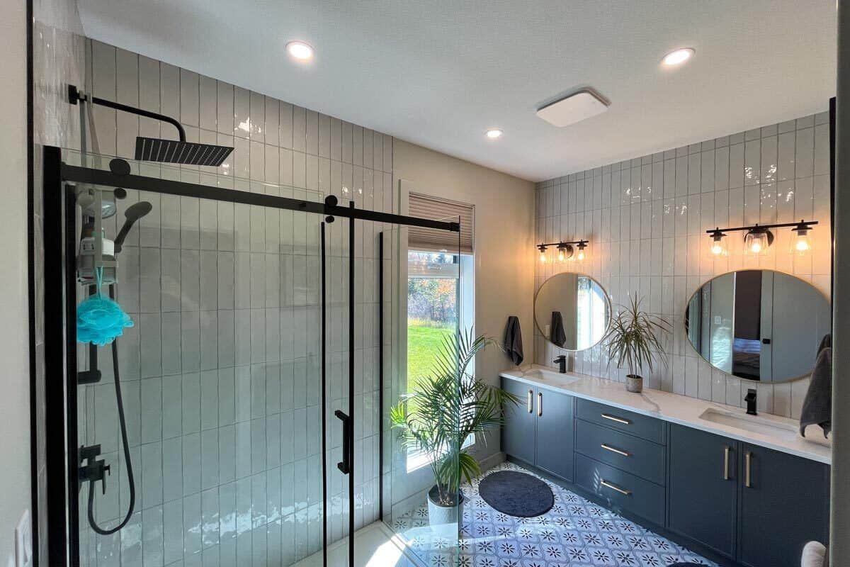 Primary bathroom with a walk-in shower and a dual sink vanity topped with round mirrors.