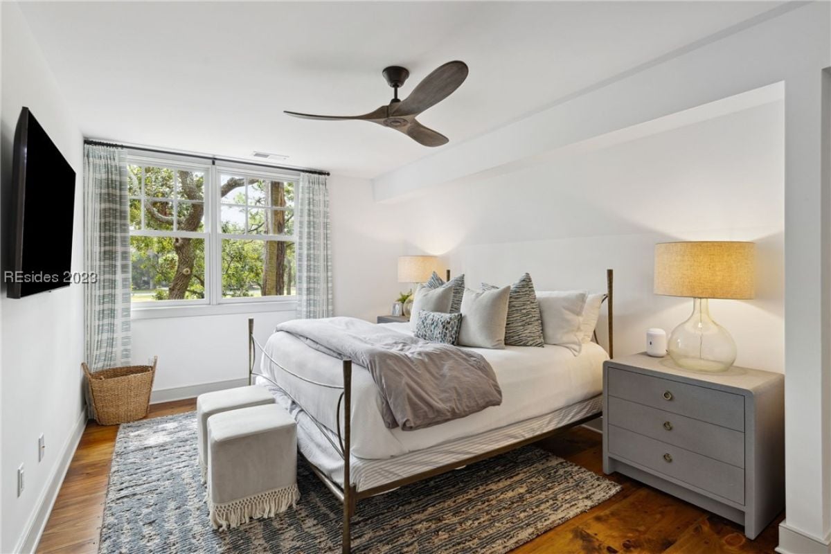 Bedroom with a large bed, TV, and glass windows.