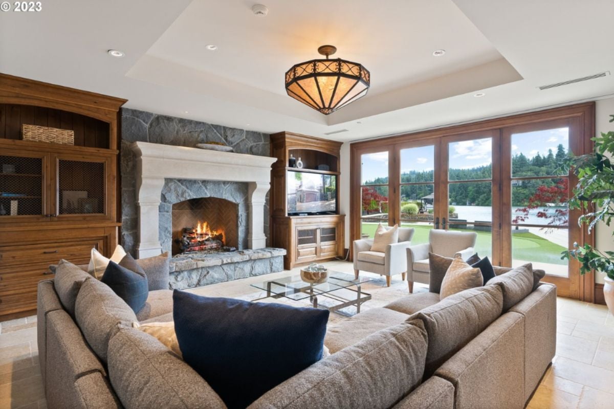 Living room with couches, chandelier, fireplace and glass doors.