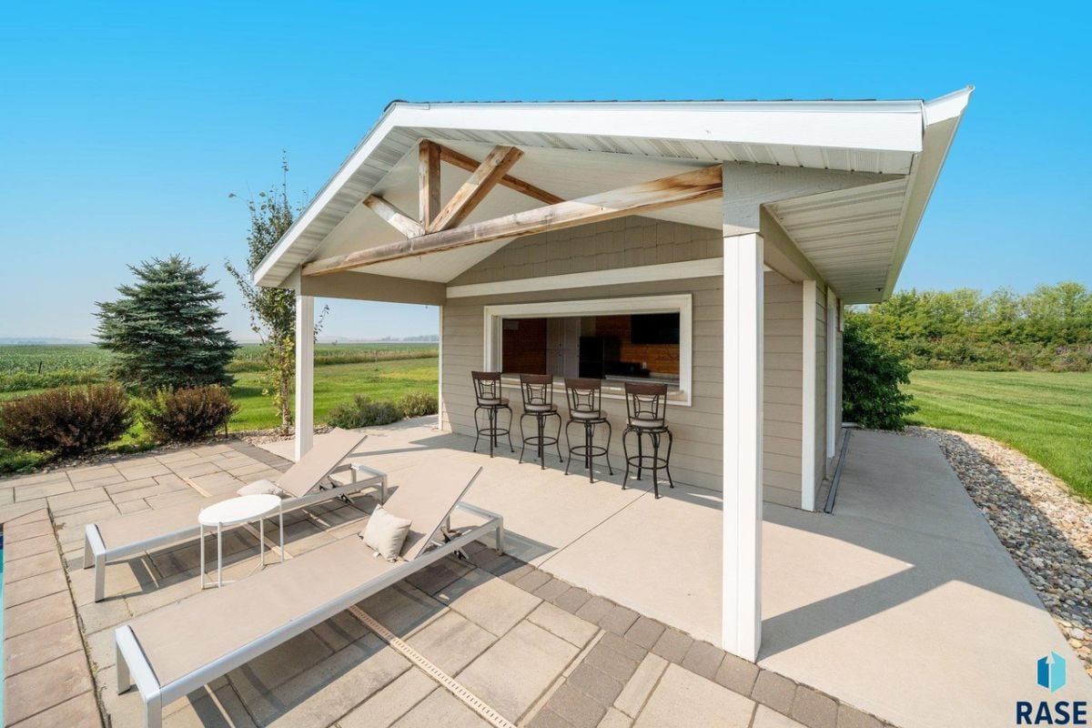Pool house bar with high chairs and lounge chairs.