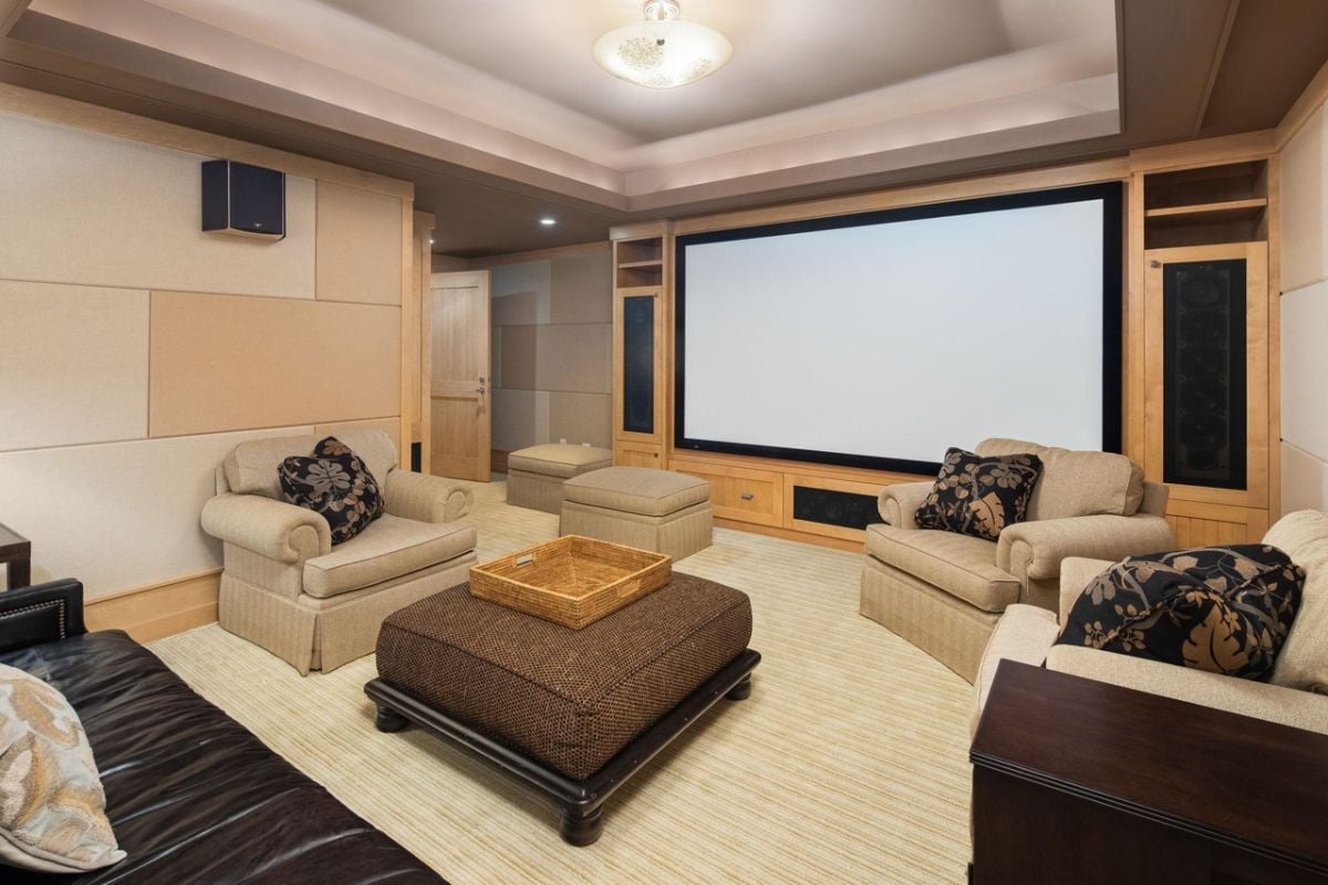 Home theater with couches, a table, and a large screen.
