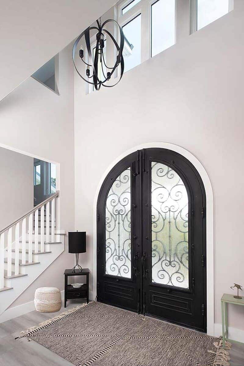 Foyer with an arched French door and a spherical chandelier that hangs from the tall ceiling.