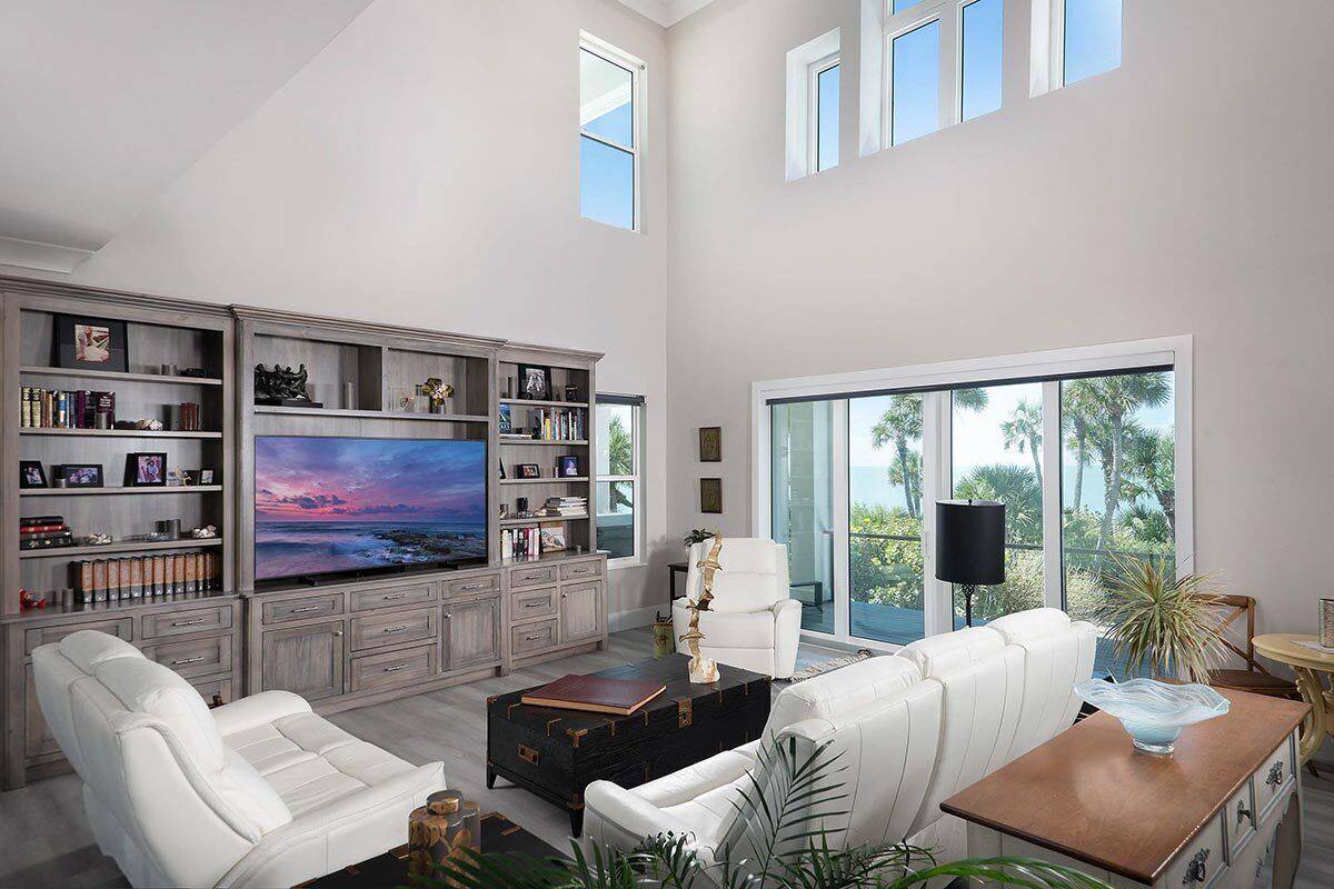 Great room with white leather seats, a TV, and sliding glass doors that open to the rear deck.