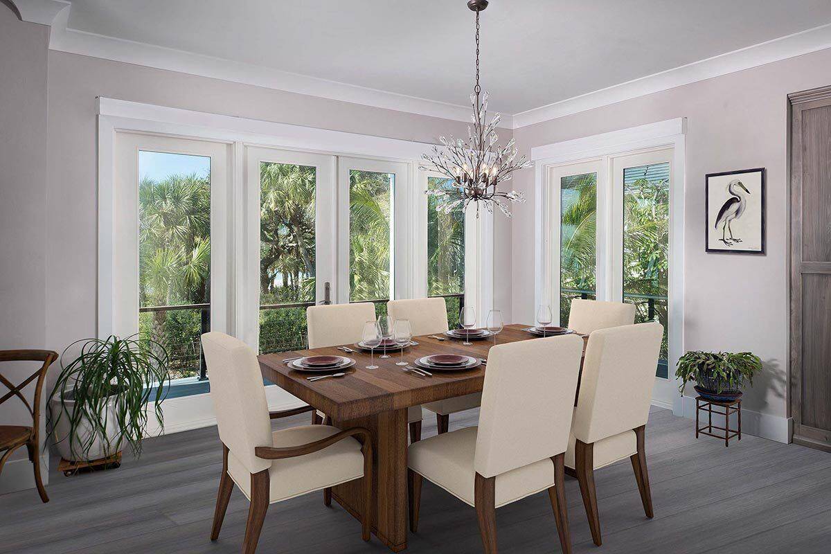 Dining room with a wooden dining table, upholstered chairs, and sliding glass doors that open to a covered lanai.
