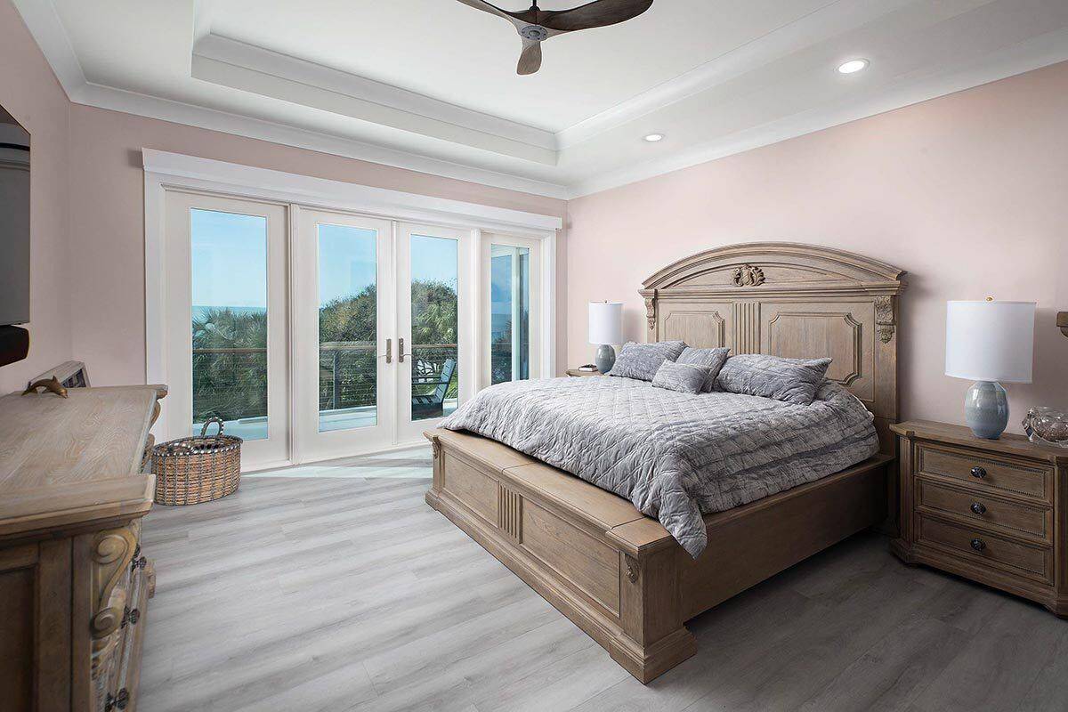 Primary bedroom with wooden furnishings, a tray ceiling, and a private balcony.