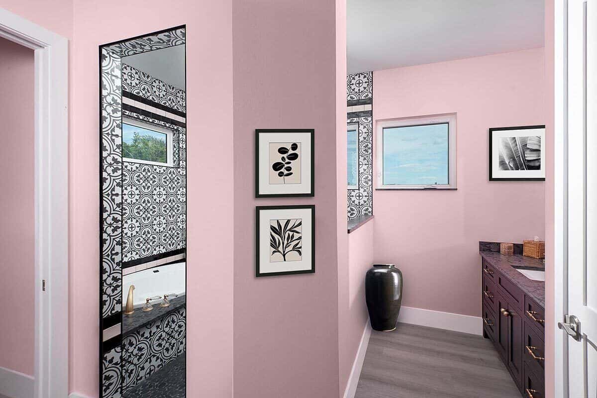 Primary bathroom with hardwood flooring and pink walls accentuated with decorative tiles and base moldings.