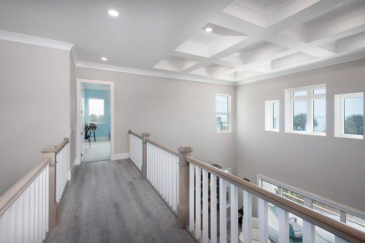 Balcony with hardwood floor and wooden railings overlooking the living space below.