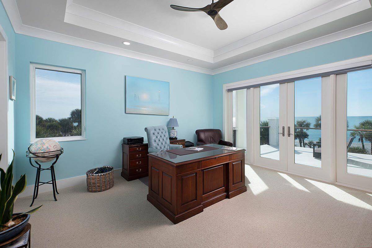 Home office with a tray ceiling, light blue walls, and outdoor access.