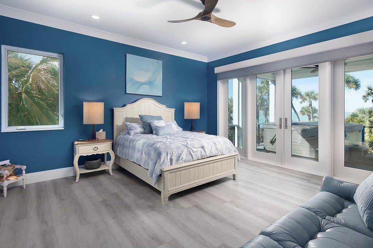 Secondary bedroom with a private deck, a tufted sofa, and a light wood bed against the deep blue wall.
