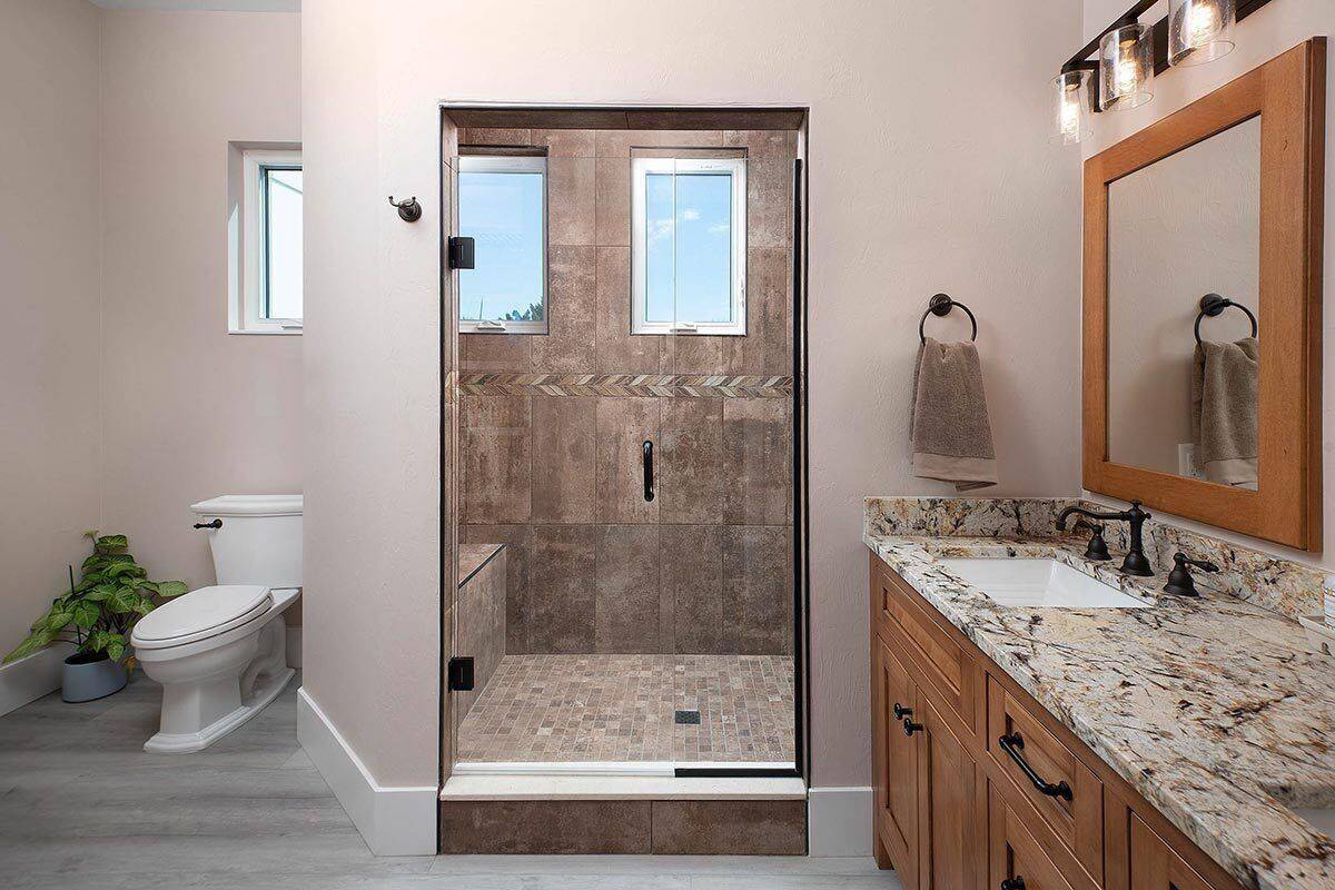 Bathroom with a wooden vanity, a toilet, and a walk-in shower with a tiled bench.