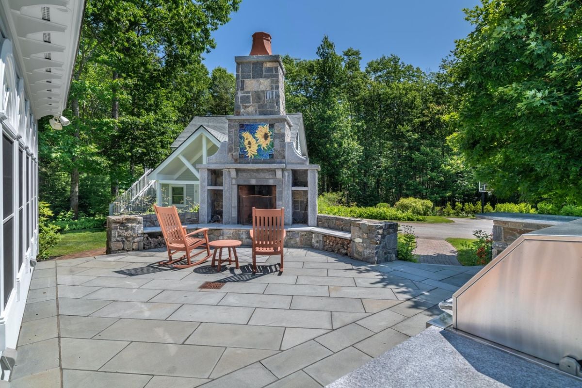Patio with chairs and a fireplace.