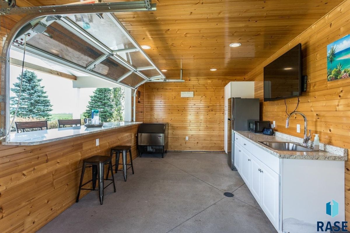 Pool house bar with a TV, sink and a refrigerator.