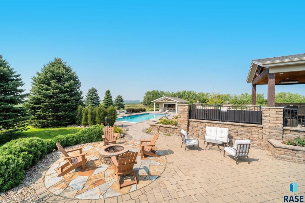 Fire pit with chairs and a pool in the background.