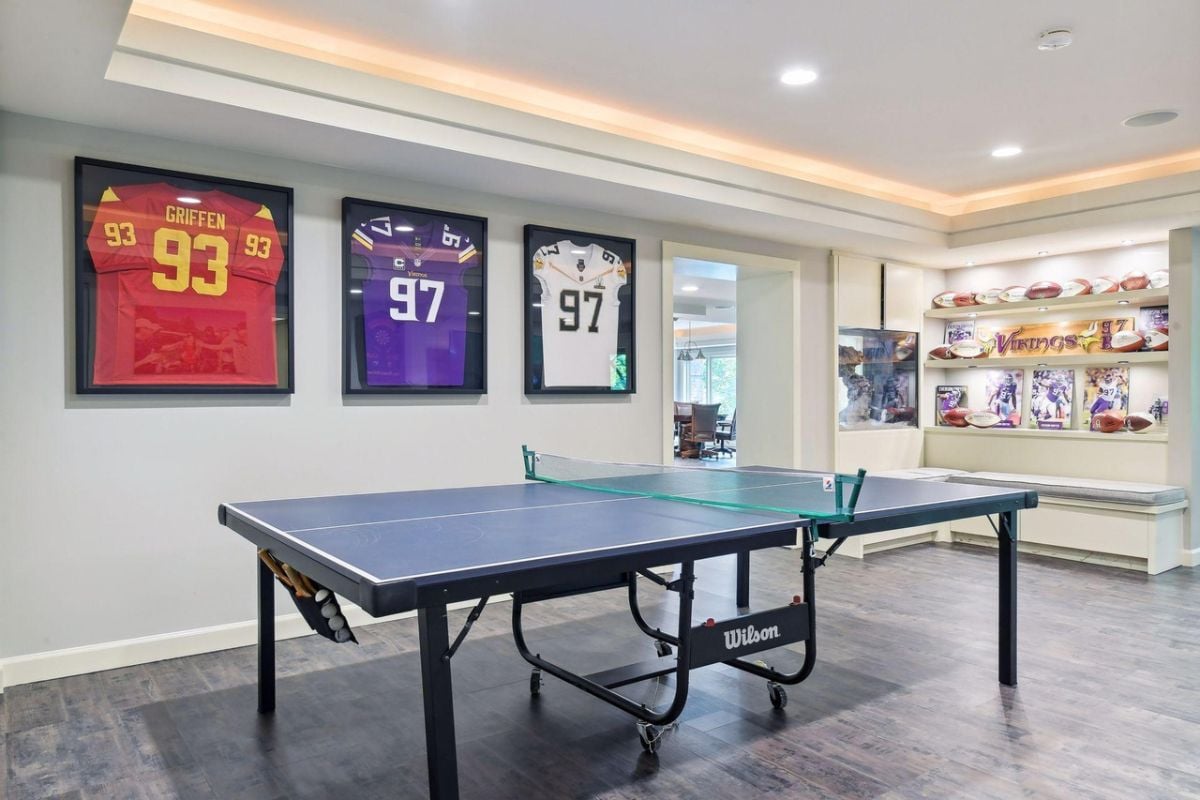 Recreation room with a table tennis and football jerseys framed on the wall.