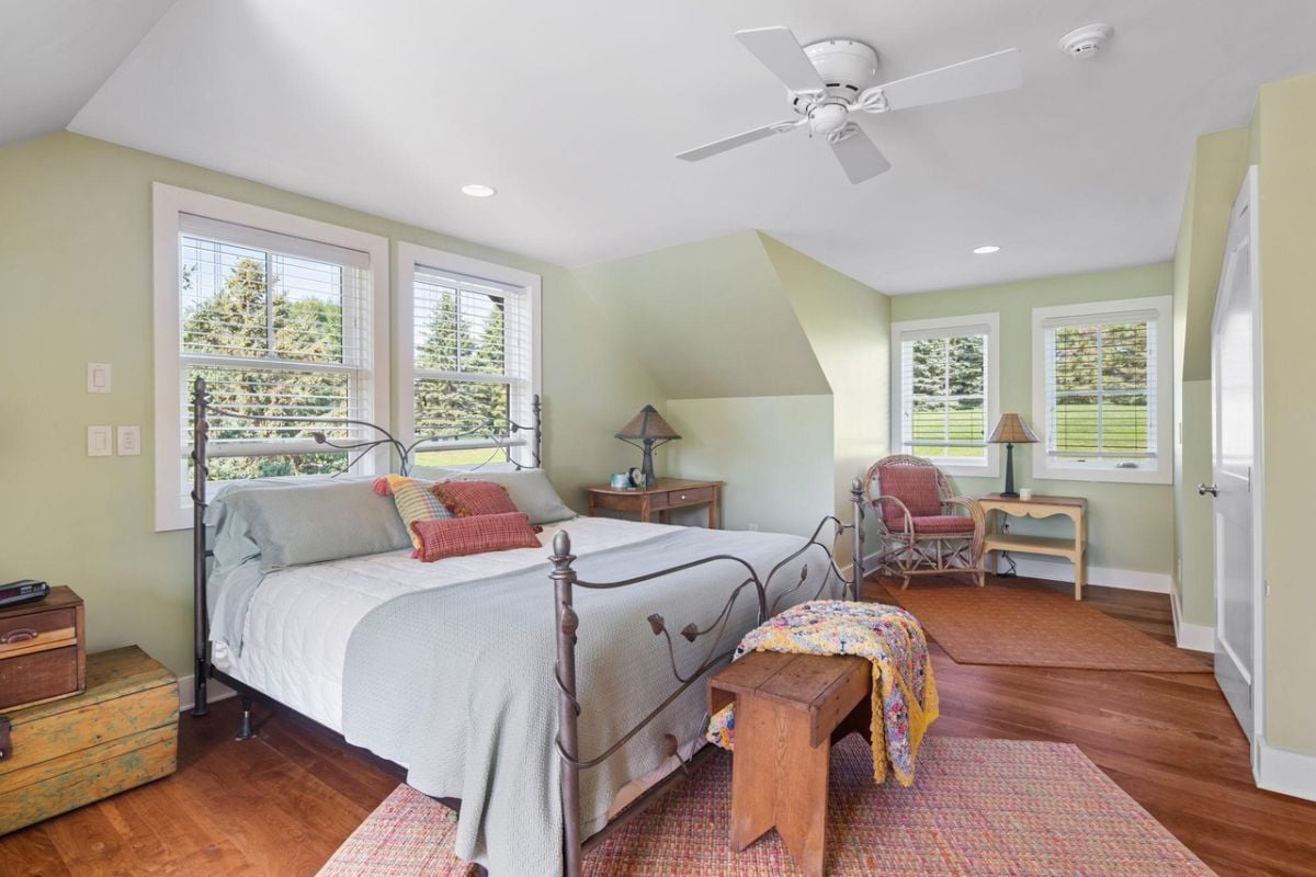 Bedroom with a large bed, wood flooring and a ceiling fan.