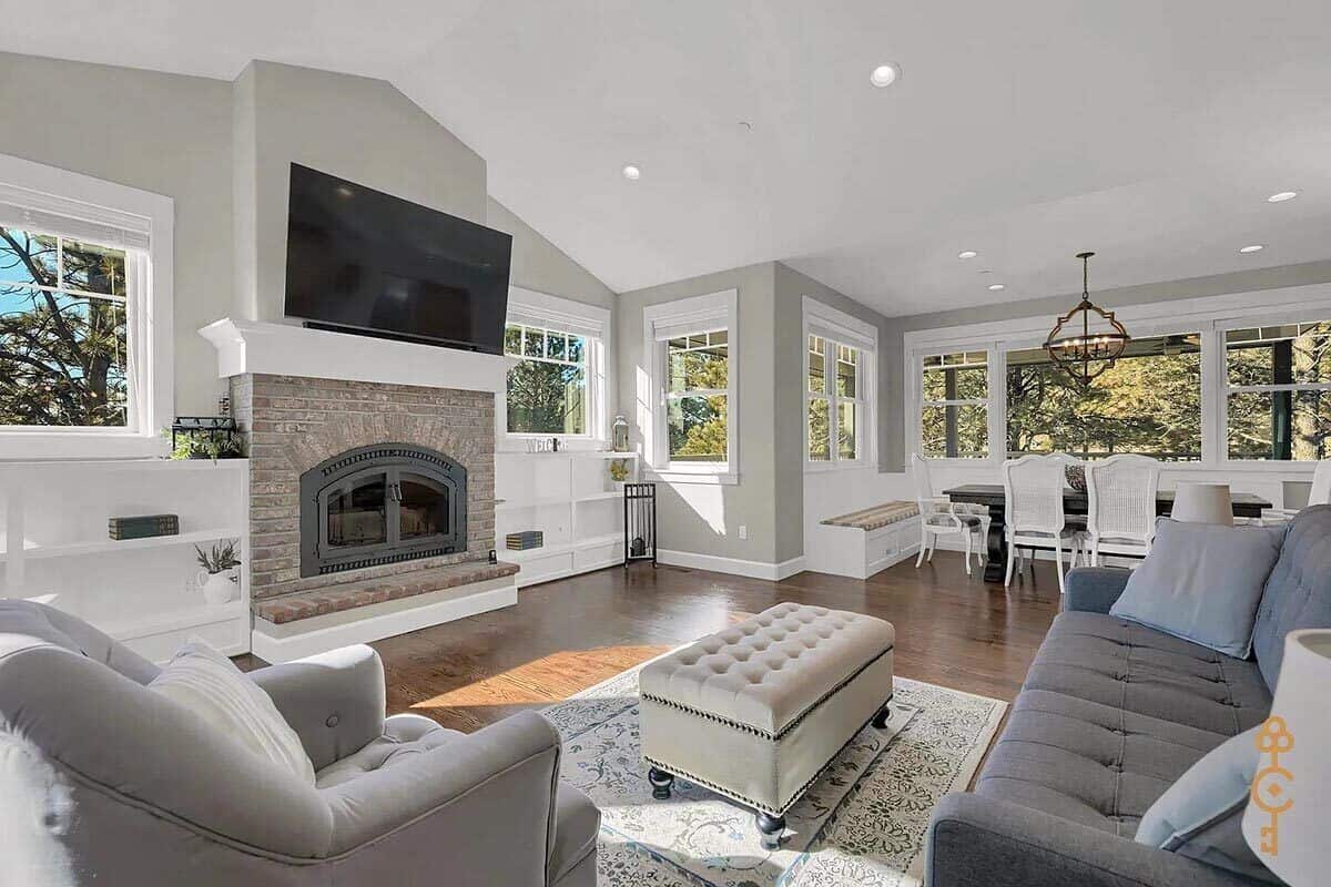 Great room with tufted seats and a stone fireplace topped with a TV.