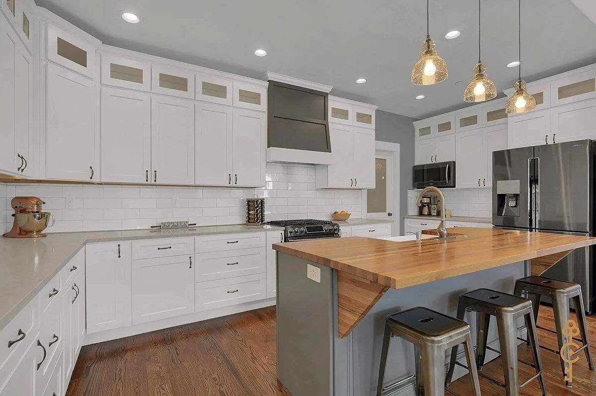 Kitchen with white cabinetry and a center island with seating for three.