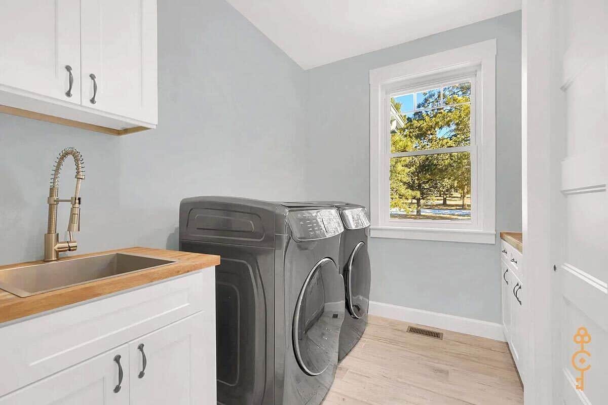 Laundry room with white cabinets, a utility sink ,and wooden countertops.