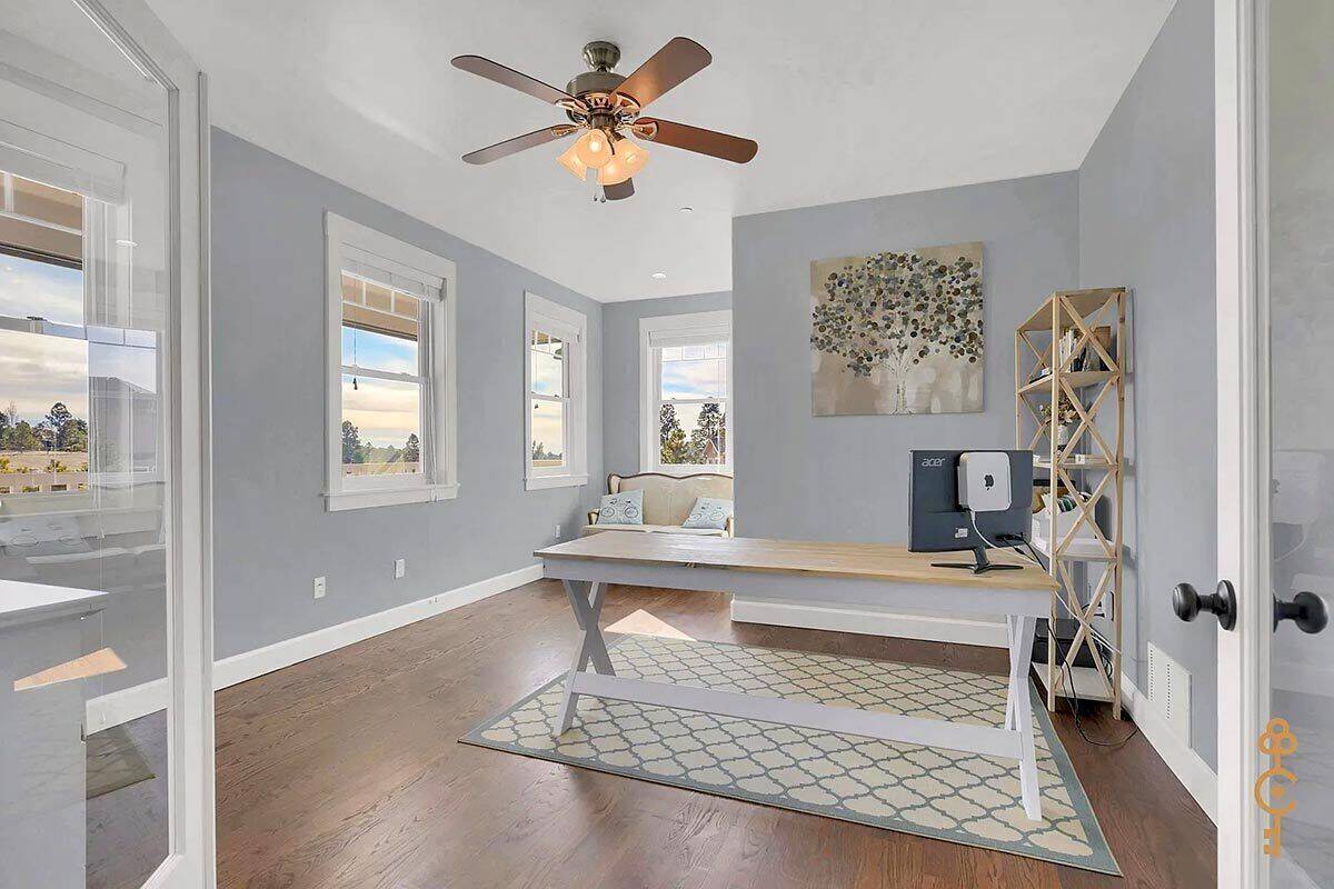 Home office with gray walls and a wooden desk over a patterned area rug.