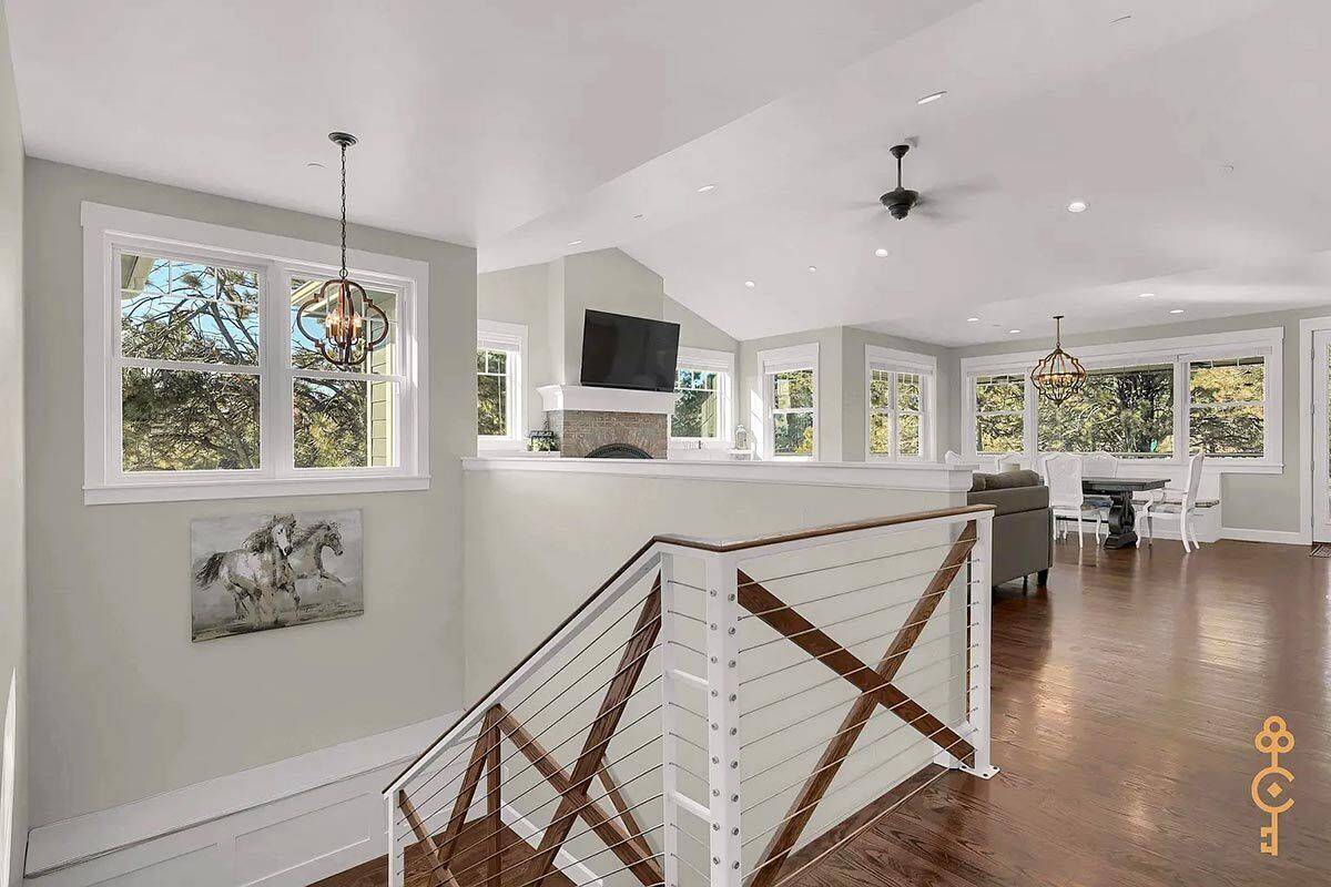 Rec room with a vaulted ceiling, hardwood flooring, and surrounding windows allowing abundant sunlight in.