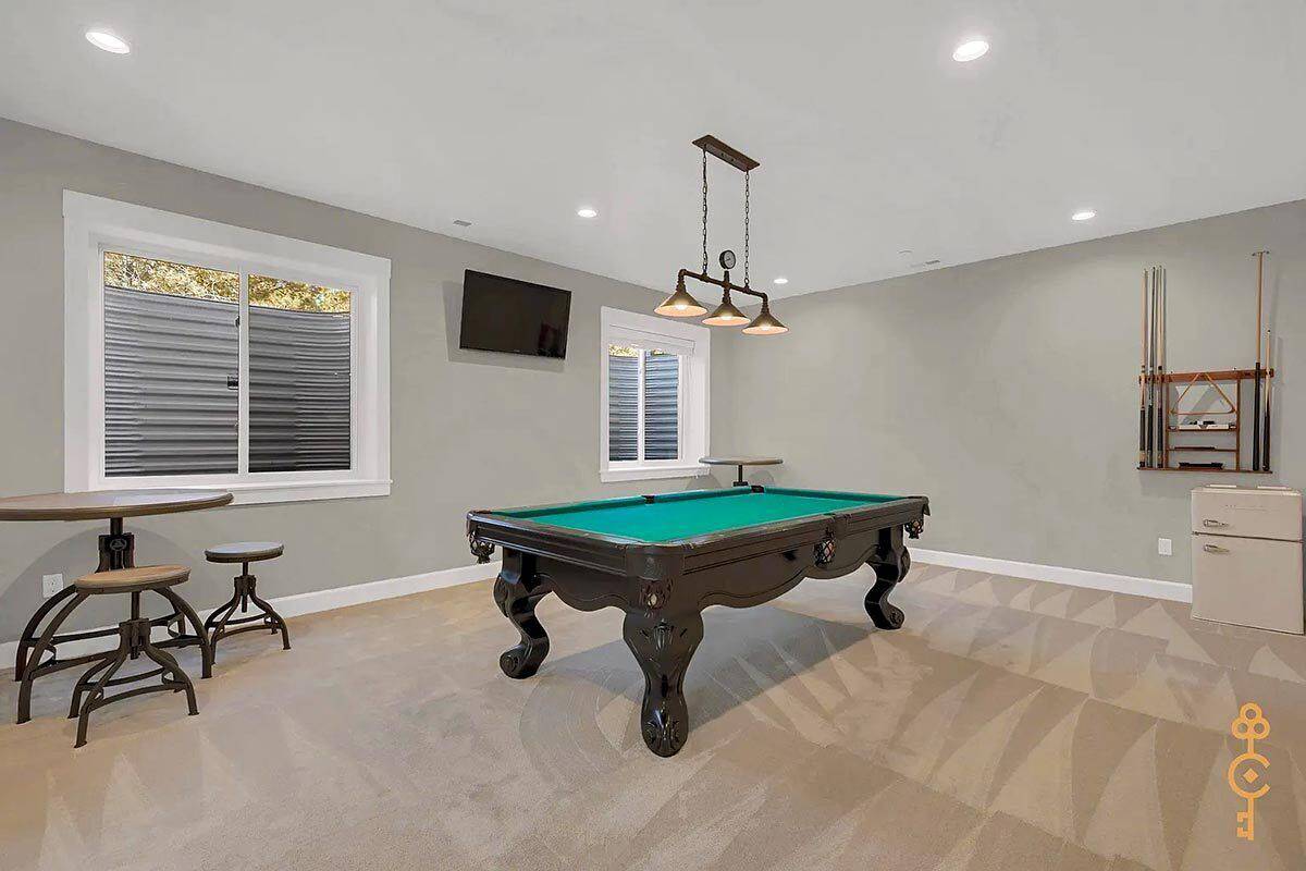 Game room with a wall-mounted TV and a billiards table over the carpeted floor.