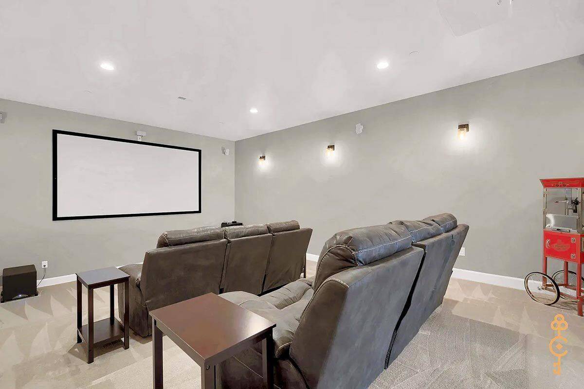 Home theater with recliner sofas, side tables, and a large screen against the gray wall.