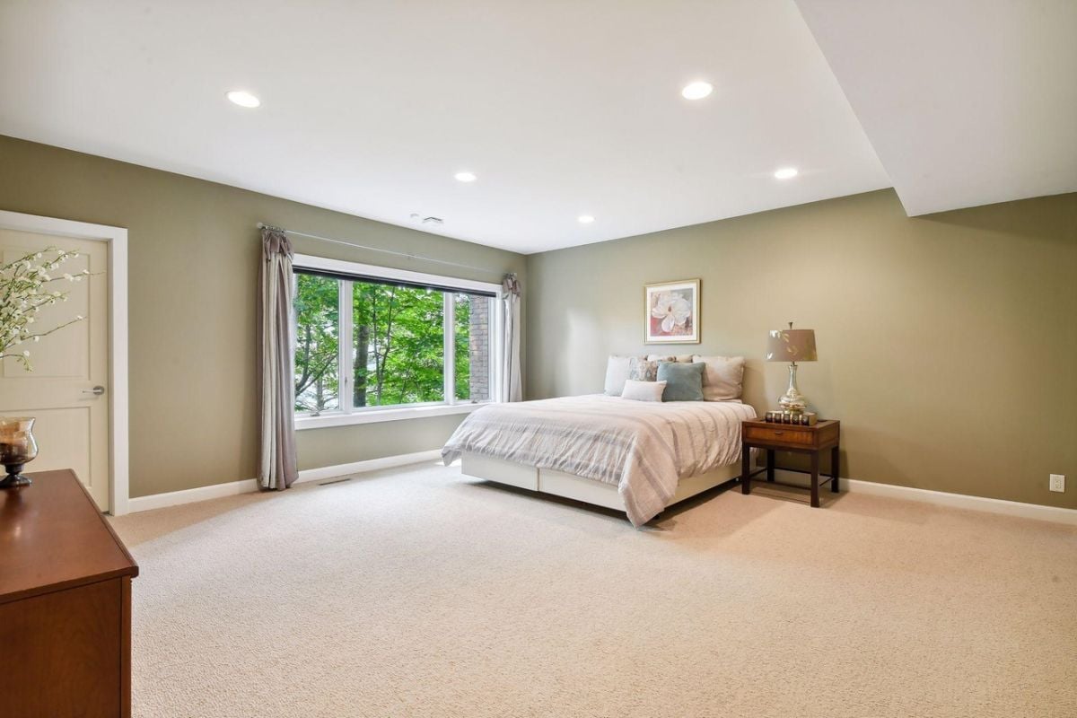 Bedroom with carpet flooring, a large bed and glass windows.