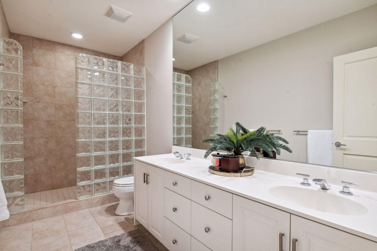 Bathroom with a sink, shower, a large mirror and a toilet.