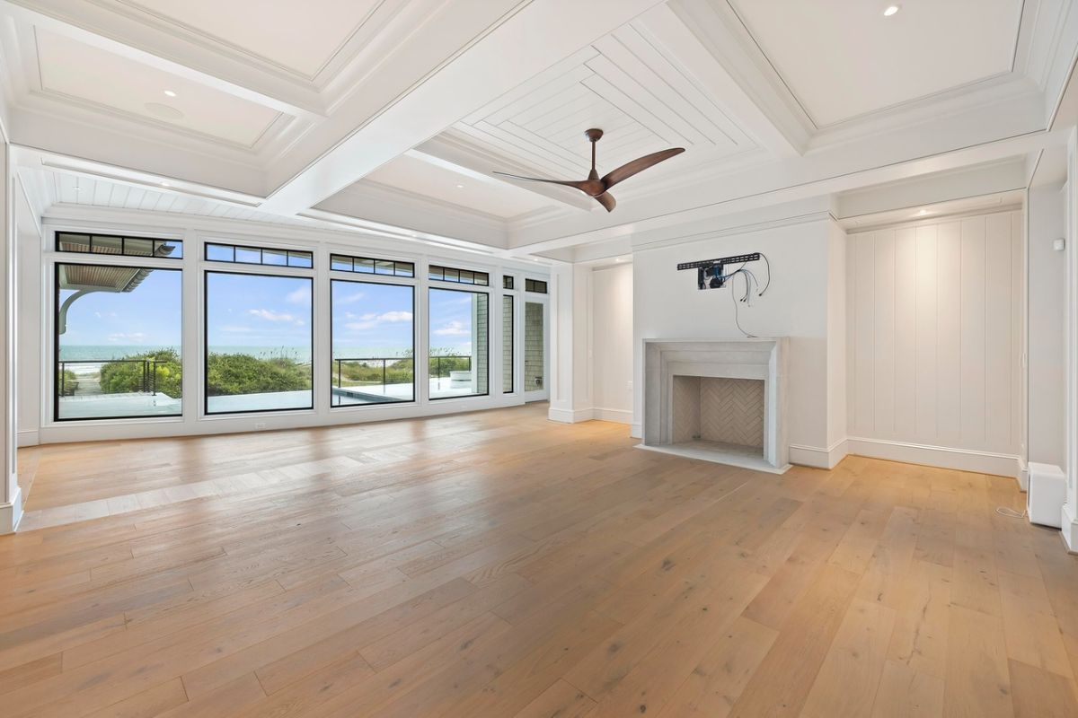 Living room with coffered ceilings, wood flooring, glass walls and a fireplace.