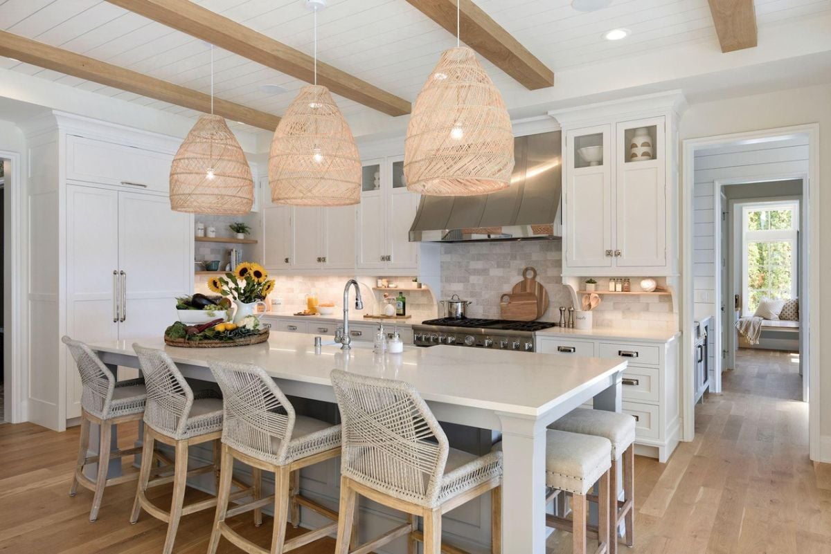 Kitchen with a large island, open beam ceiling, custom lights, custom cabinets and wood flooring.