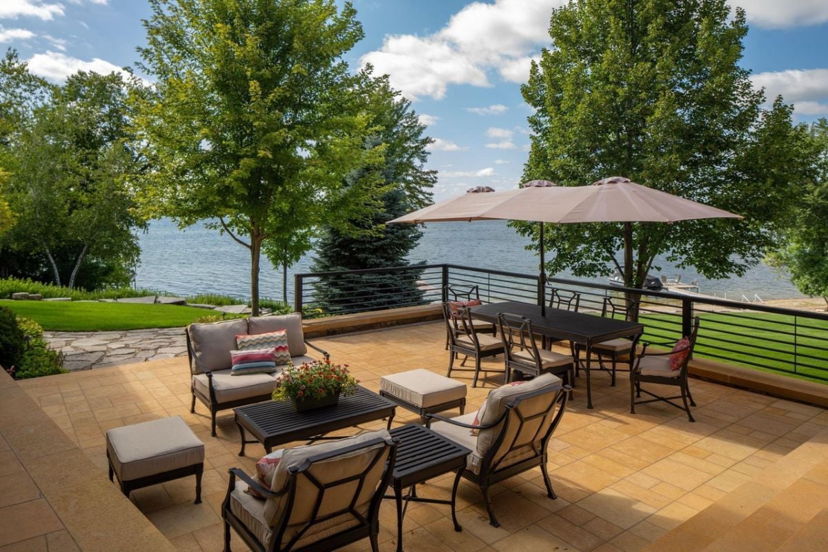 Balcony with tables, chairs and a view of the lake.