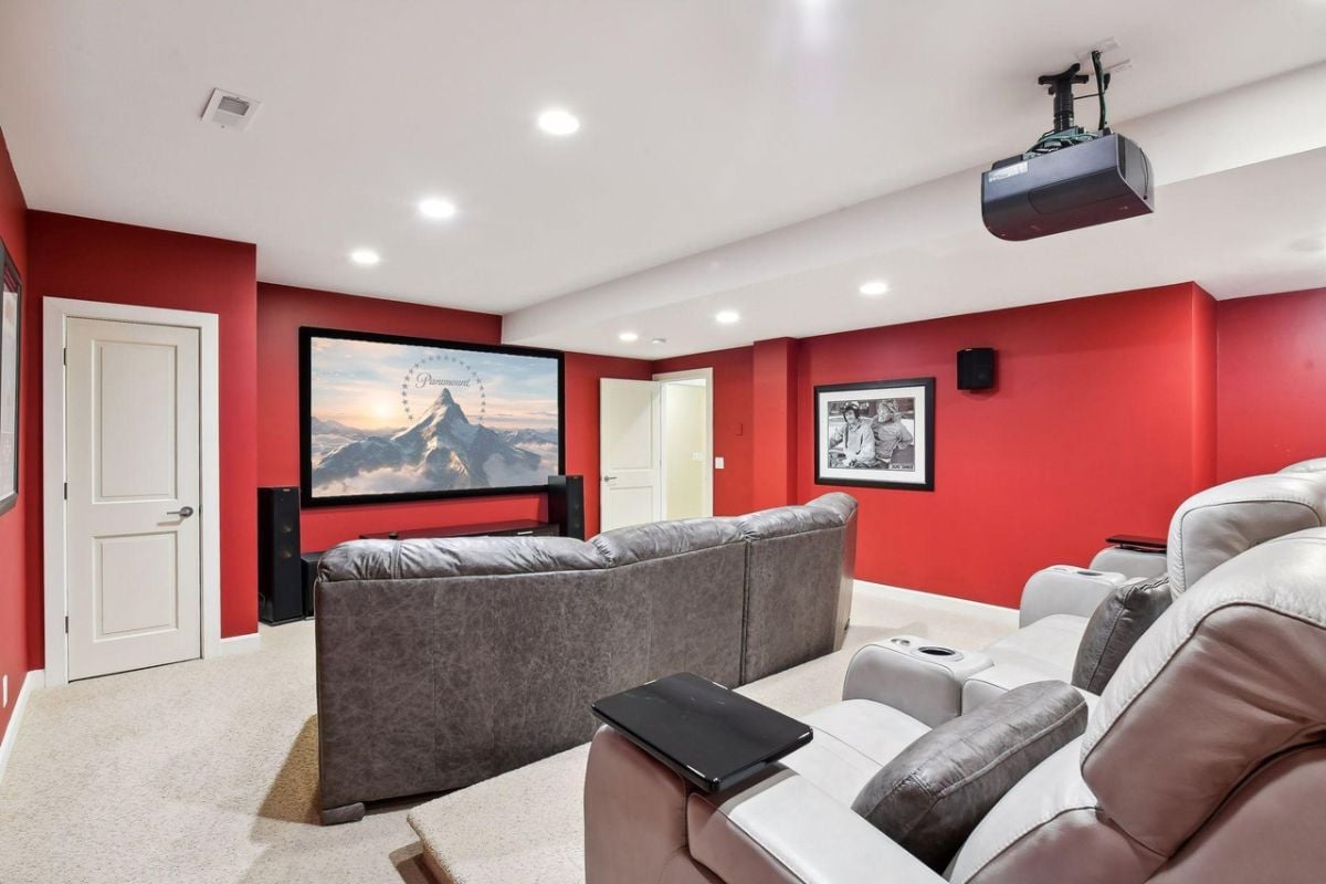 Home theater with carpet flooring, reclining chairs and a large screen.