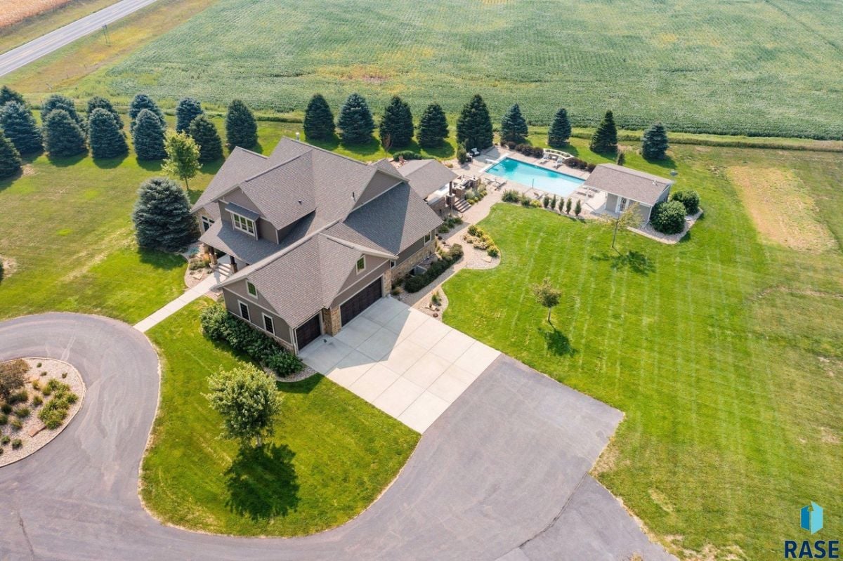 Aerial view of the property with spacious driveway and a large green lawn.