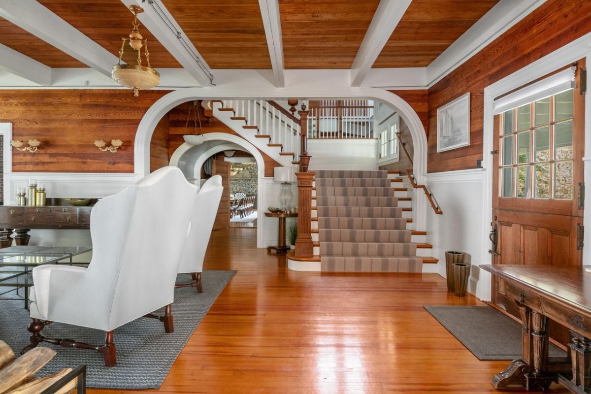 Living room with couches, rug, chandelier, wood flooring and staircase.