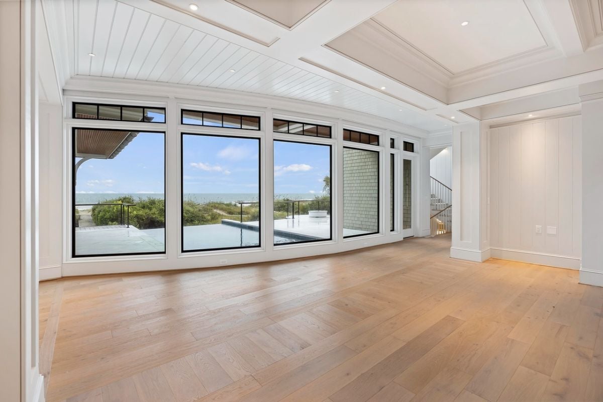 Living room with coffered ceilings, wood flooring, glass walls and custom lights.