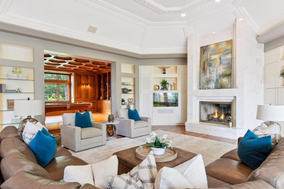 Living room with couches, wooden floors, a large rug and a fireplace.