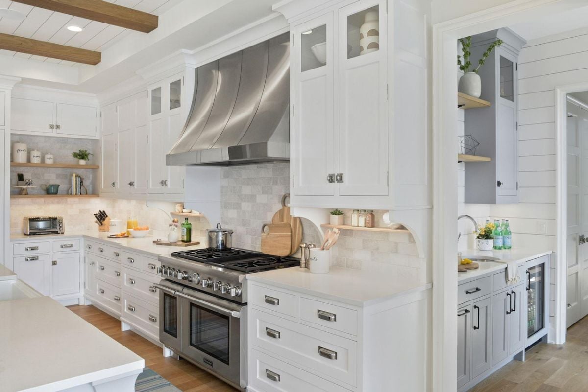 Kitchen with a large island, open beam ceiling, custom lights, custom cabinets and wood flooring.
