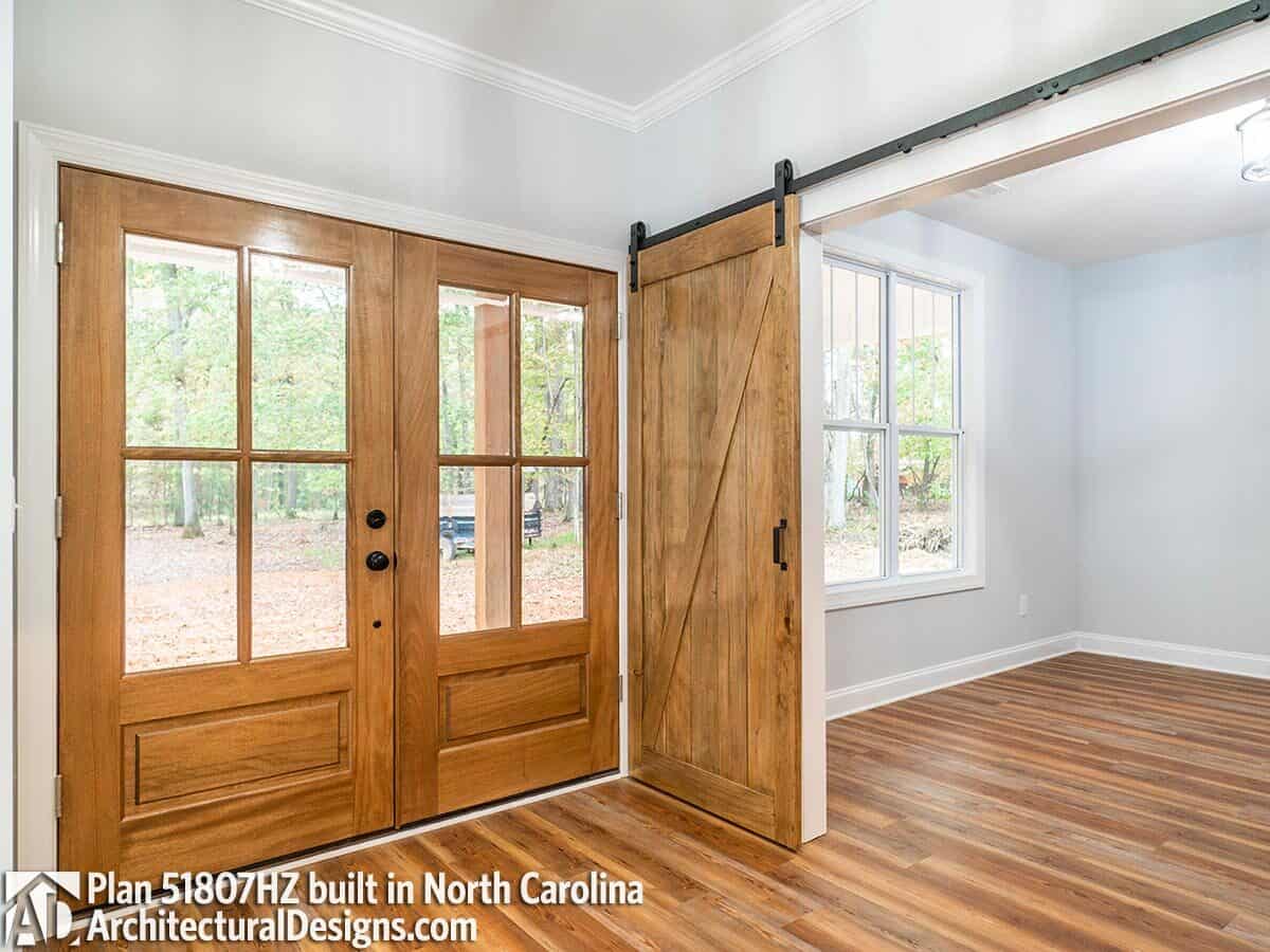 Foyer with a French entry door and sliding barn doors that open to the home office.