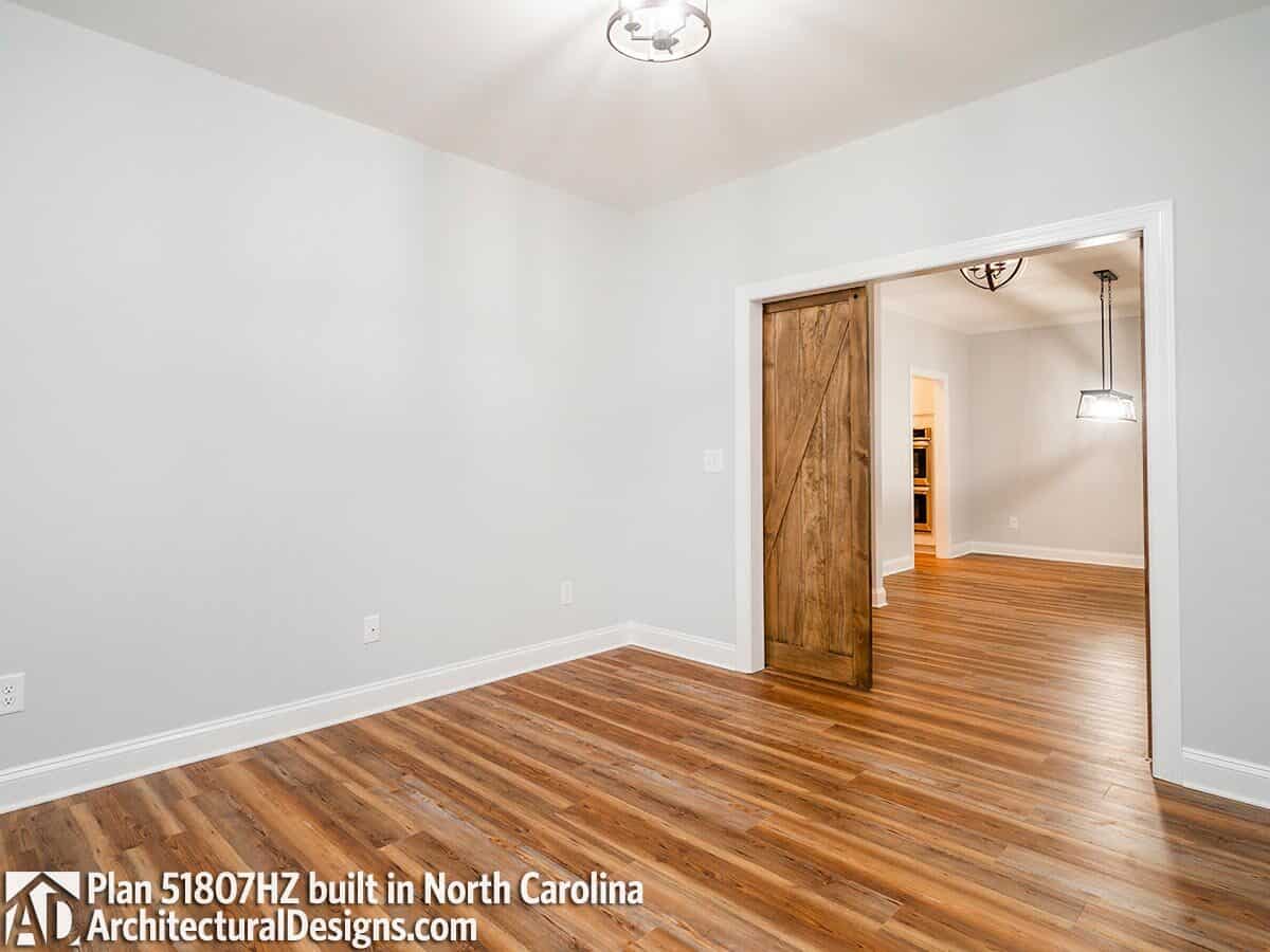 Study with hardwood flooring and sliding barn doors.