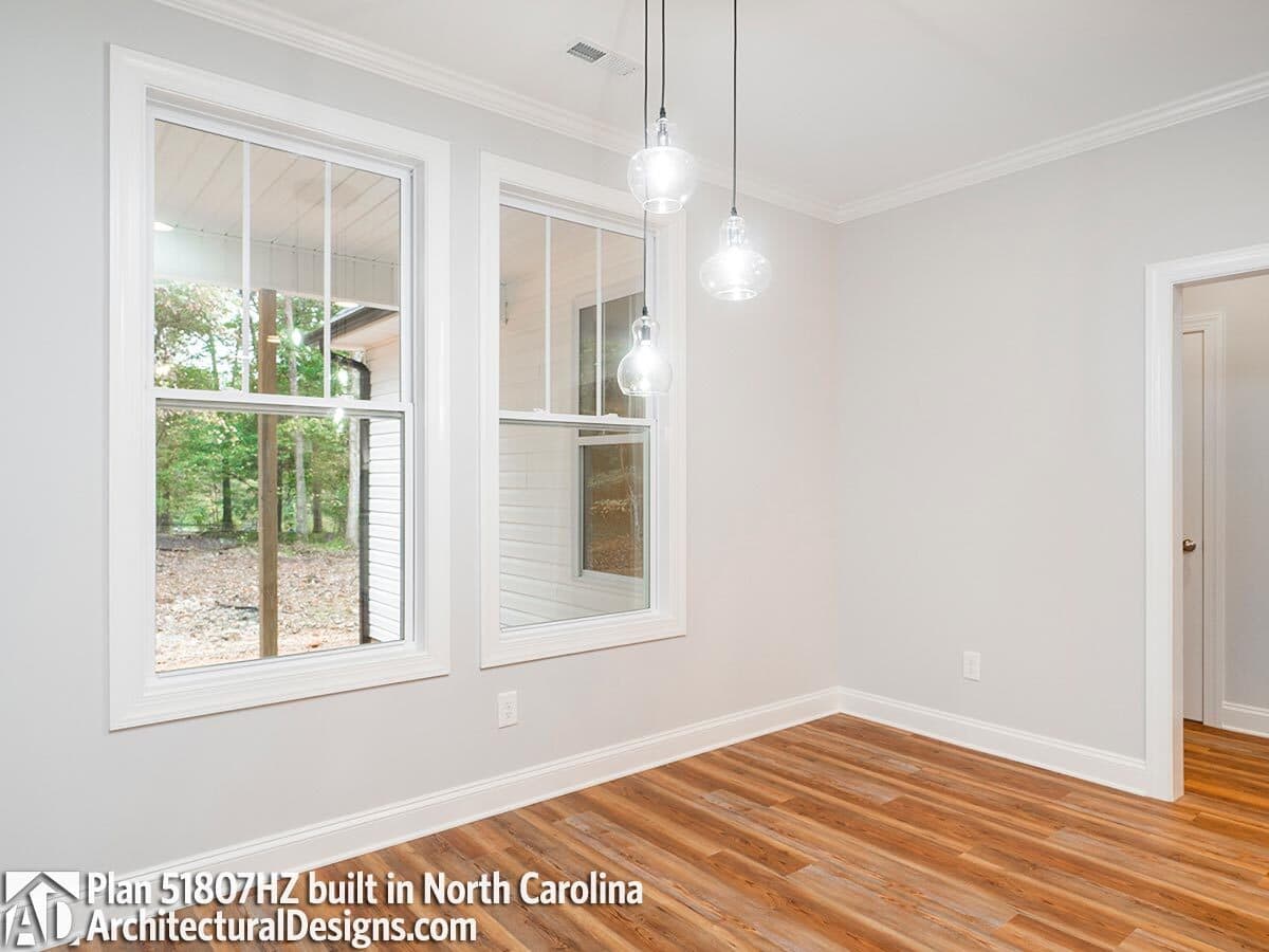 Breakfast nook with glass-globe pendants and white-framed windows overlooking the back porch.