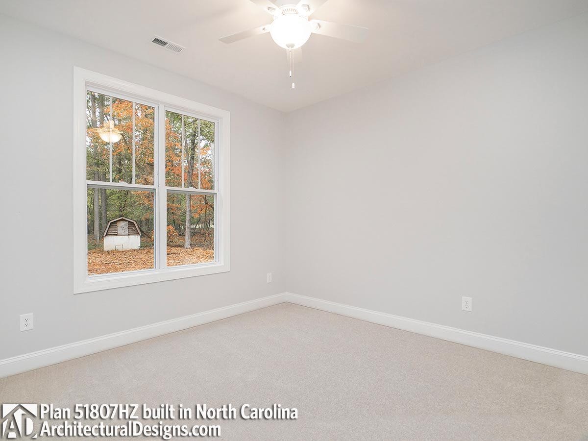 Secondary bedroom with carpeted floor and white walls lined with base moldings.