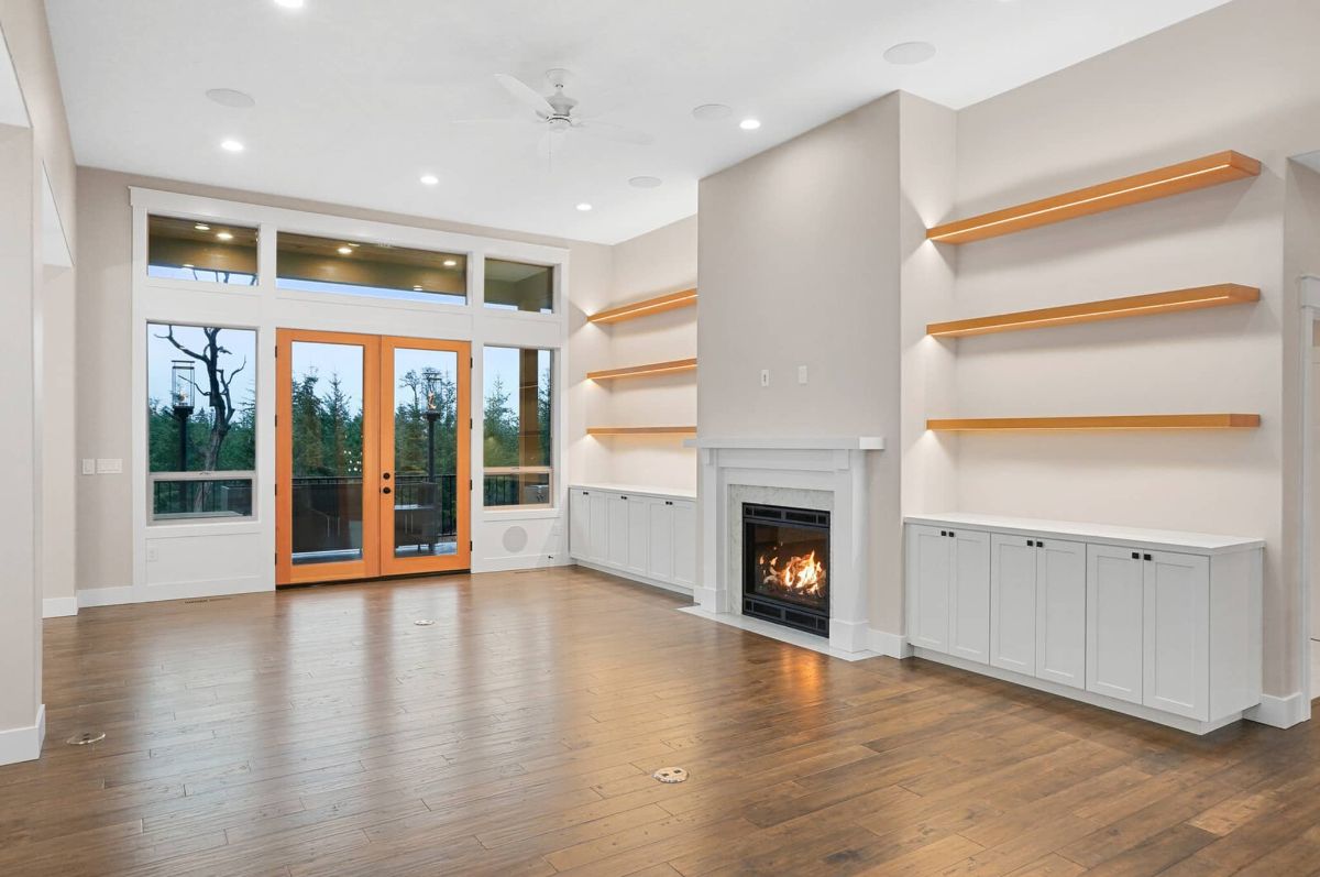 Living room with a fireplace, wooden floors, custom lights and glass doors.