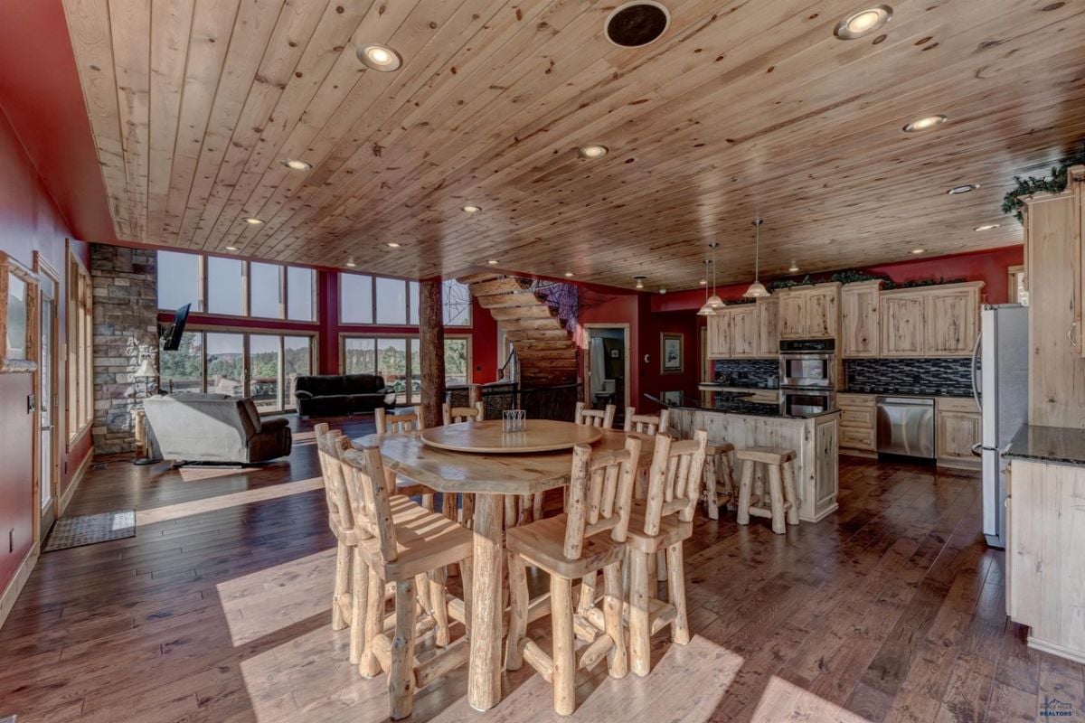 Dining room with a wooden table, chairs, custom lights and wood flooring.