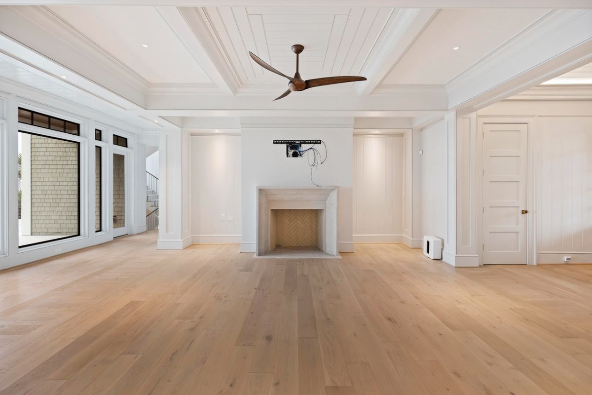 Living room with coffered ceilings, wood flooring, glass walls and a fireplace.