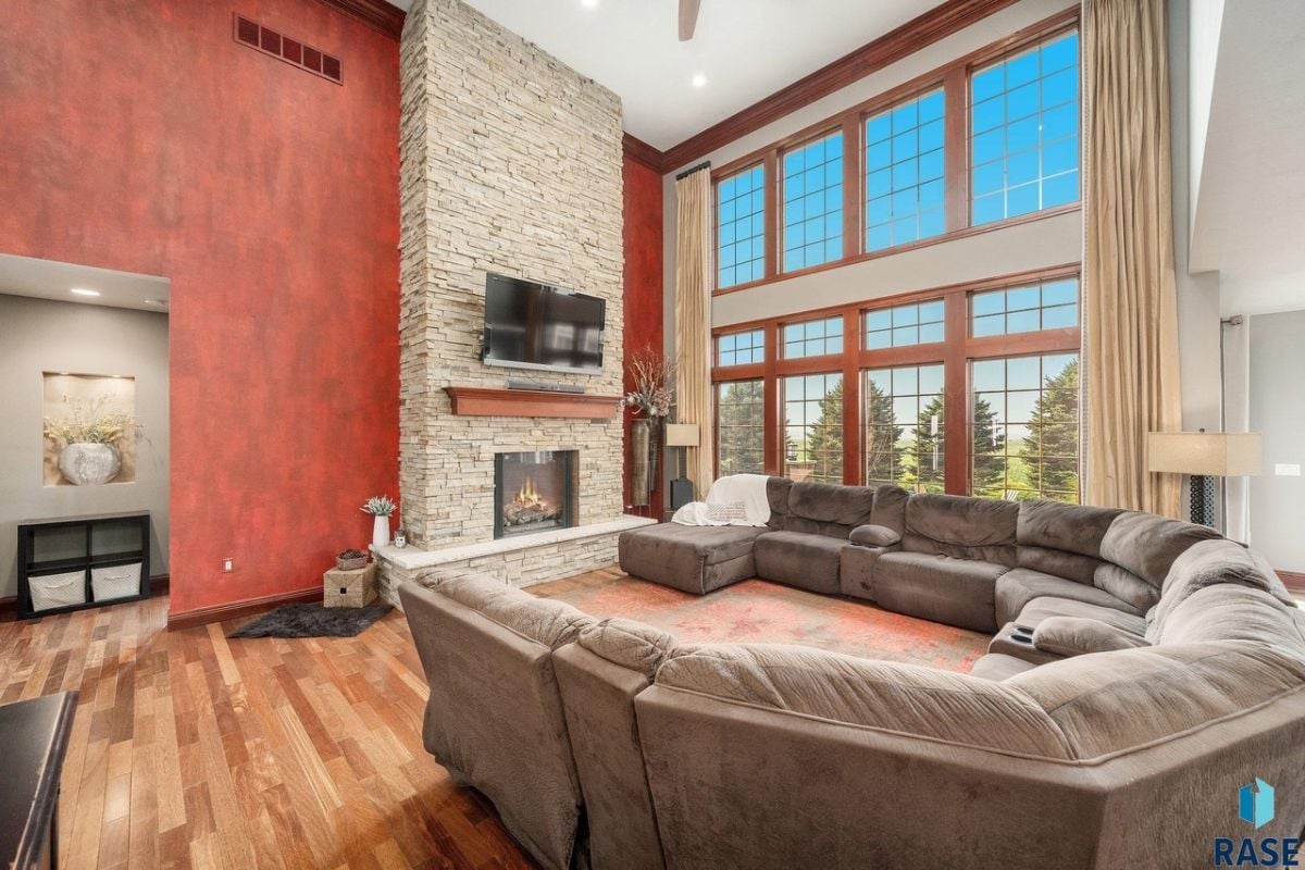 Living room with couches, TV, fireplace and large glass windows.