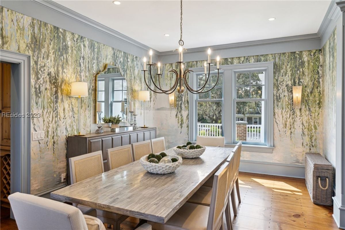 Dining room with a large wooden table, chairs and a chandelier.