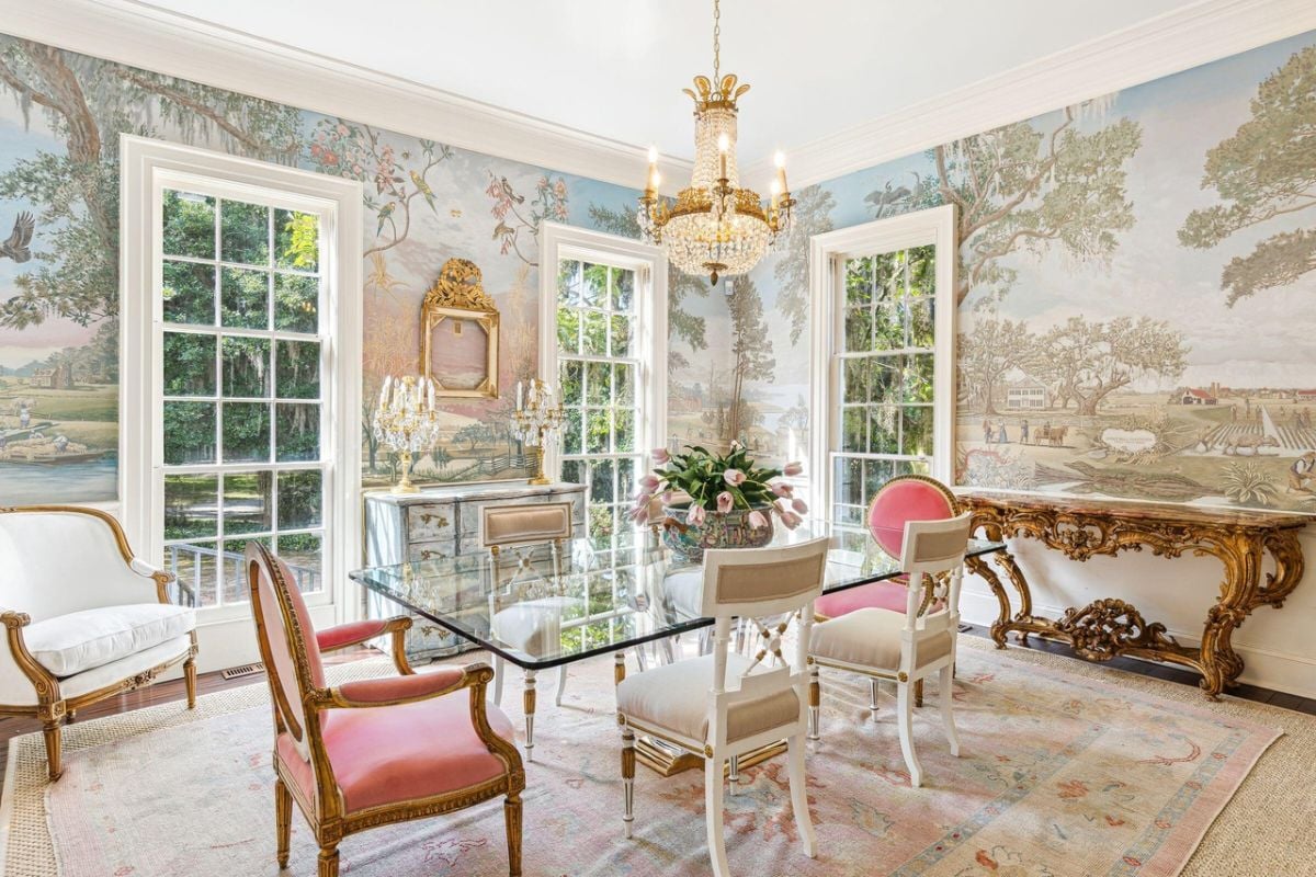 Dining room with a large glass table, chairs, chandelier and glass windows.